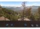 Stunning view of the distant mountains, a hillside covered in trees, and roof with skylights in the foreground at 4560 Hilltop Rd, Evergreen, CO 80439