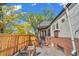 Exterior view showcasing a fenced backyard, brick accents, and mature trees offering privacy and curb appeal at 1300 Cherry St, Denver, CO 80220