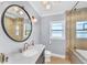 Bright bathroom features a large, round mirror, marble countertop, and a glass-enclosed shower and tub at 1300 Cherry St, Denver, CO 80220