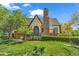 Charming home featuring a lush front lawn, brick chimney, and a distinctive arched front door at 1300 Cherry St, Denver, CO 80220