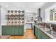 Inviting kitchen featuring green cabinets, stone countertops, decorative tile backsplash and stainless steel appliances at 1300 Cherry St, Denver, CO 80220