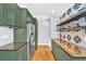 Gorgeous kitchen features green cabinetry, hardwood floors, stainless steel appliances, and accent tile backsplash at 1300 Cherry St, Denver, CO 80220