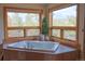 Relaxing bathtub with large windows offering views of the surrounding greenery at 7076 Boreas Rd, Larkspur, CO 80118