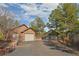 A beautiful exterior of a stone garage in a wooded community with attached garages and an asphalt driveway at 7076 Boreas Rd, Larkspur, CO 80118