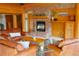 Cozy living room features a brick fireplace, wood paneling, and comfortable leather furniture at 7076 Boreas Rd, Larkspur, CO 80118