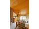 Cozy main bedroom with a brick fireplace, wood ceiling, and a large window offering natural light at 7076 Boreas Rd, Larkspur, CO 80118