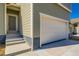 Side view of a new house with white garage door and gray entrance, with a lawn under construction at 4114 Estrella St, Brighton, CO 80601