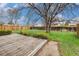 Large backyard with wooden deck, grass, bushes, and mature tree at 726 Mobile St, Aurora, CO 80011