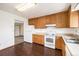 Well-lit kitchen featuring wood cabinets, white appliances, and dark laminate flooring at 726 Mobile St, Aurora, CO 80011