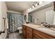Bathroom with granite countertop, wood cabinets, large mirror, and a shower-tub combo at 13642 Wrangler Way, Mead, CO 80542