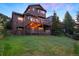 Picturesque exterior with a spacious deck, ambient string lights, and lush greenery, creating a cozy outdoor retreat at 24045 High Meadow Dr, Golden, CO 80401