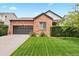 Charming brick home featuring a well-manicured lawn and attached two-car garage at 13983 E 104Th Pl, Commerce City, CO 80022
