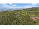 A distant aerial view captures the home, nestled among mature trees, with a stunning mountain backdrop at 11222 Conifer Mountain Rd, Conifer, CO 80433
