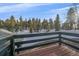 Scenic view from the deck overlooking snow covered terrain, with mature trees set against a blue sky at 11222 Conifer Mountain Rd, Conifer, CO 80433