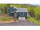 Two-story home with a wooden porch, two car garage and forest in the background at 11222 Conifer Mountain Rd, Conifer, CO 80433