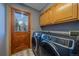 Well-equipped laundry room with modern washer and dryer, wood cabinets, and an exterior door at 11222 Conifer Mountain Rd, Conifer, CO 80433