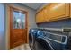 Well-equipped laundry room with modern washer and dryer set, wooden cabinets, and exterior door at 11222 Conifer Mountain Rd, Conifer, CO 80433