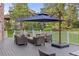 Grey deck with patio furniture, white railing, umbrella, and view of the beautiful, wooded backyard at 5428 Golden Currant Way, Parker, CO 80134