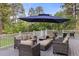 Grey deck with patio furniture, umbrella, white railing, and view of the beautiful, wooded backyard at 5428 Golden Currant Way, Parker, CO 80134