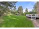 Lush backyard featuring a large lawn, swing set, and a deck with an umbrella and furniture at 5428 Golden Currant Way, Parker, CO 80134