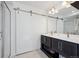 Elegant bathroom showcasing a sliding barn door, dual vanity sinks, and modern lighting at 18012 E 107Th Ave, Commerce City, CO 80022