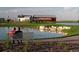 Scenic pond view with couple on bench, surrounded by lush landscaping and community buildings at 18012 E 107Th Ave, Commerce City, CO 80022