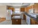 Well-lit kitchen with island, wood cabinetry, and white appliances at 233 Cherokee Ct, Brighton, CO 80603