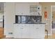 A wet bar featuring white cabinetry, dark granite countertops, and glass shelving for drinkware storage at 945 Niagara St, Denver, CO 80220