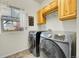 Convenient laundry room featuring modern washer and dryer units, storage cabinets, and a window for natural light at 12873 E 108Th Ave, Commerce City, CO 80022