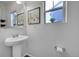 Simple powder room with pedestal sink, decorative mirror, and natural light from a window at 12873 E 108Th Ave, Commerce City, CO 80022