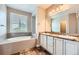 Bright bathroom featuring double sinks, tile floors, granite countertop, a large soaking tub and natural light at 606 E Dry Creek Pl, Littleton, CO 80122