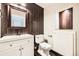 Modern bathroom features dark wooden accents, a white sink vanity, and a matching framed mirror at 606 E Dry Creek Pl, Littleton, CO 80122