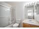 Clean bathroom with shower-tub combo, wood vanity, modern lighting, and sliding glass shower doors at 1965 E 127Th Cir, Thornton, CO 80241