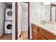 Well-lit bathroom boasts charming wood cabinets and stacked washer and dryer at 8460 Decatur St # 138, Westminster, CO 80031