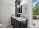 Bathroom featuring a black vanity, marble countertop, vanity mirror, and natural lighting at 5653 E Southmoor Cir, Englewood, CO 80111