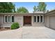 Charming ranch-style home features a brick facade, wood door, manicured landscaping, and an inviting entryway at 5653 E Southmoor Cir, Englewood, CO 80111