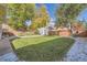 Large grassy backyard with mature shade trees, white rock landscaping, and privacy fence at 4212 Lowell Blvd, Denver, CO 80211