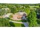 Gorgeous aerial view of a stately brick home with manicured grounds, a circular driveway, and lush trees at 5700 S Steele St, Greenwood Village, CO 80121
