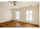 Spacious empty room with hardwood floors, white walls, a ceiling fan, and shuttered windows at 5700 S Steele St, Greenwood Village, CO 80121