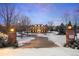 Elegant brick home with a long driveway and snow-covered landscaping at dusk at 5700 S Steele St, Greenwood Village, CO 80121