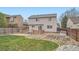 Back of house featuring a stone patio, garden plots, and a lush lawn at 5130 S Wenatchee St, Aurora, CO 80015