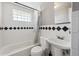 Bathroom featuring all-white tiled walls, shower-tub combo and a white pedestal sink at 6690 Albion St, Commerce City, CO 80022