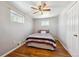 Bedroom with wood floors, a ceiling fan, and white walls with a bed with red, white and black comforter at 6690 Albion St, Commerce City, CO 80022
