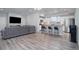 Open-concept living room featuring a gray sofa, wood floors, and a view of the kitchen with a large island at 28418 E 8Th Pl, Watkins, CO 80137