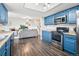 Open kitchen with stainless steel appliances, blue cabinets, and hardwood floors adjoins a living room with staircase at 1080 S Yampa St, Aurora, CO 80017