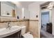 Bathroom featuring a vanity, medicine cabinet, tiled walls, and a view into the hall at 1328 S Zuni St, Denver, CO 80223