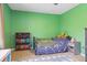 This bedroom features vibrant green walls, a cozy bed, and a bookshelf with colorful books and dinosaur-themed decor at 6213 S Lima Way, Englewood, CO 80111