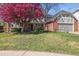 Charming brick home featuring a well-manicured lawn, vibrant flowering tree, and attached two-car garage at 6213 S Lima Way, Englewood, CO 80111