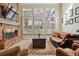 Cozy living room featuring a brick fireplace, large windows, hardwood floors, and comfortable leather seating at 6213 S Lima Way, Englewood, CO 80111