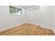 Bright, minimalist bedroom with hardwood floors, white walls, and closet space at 5573 S Huron St, Littleton, CO 80120
